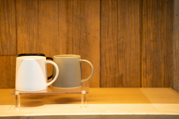 Fototapeta na wymiar Three-color coffee mug on the floor in a wooden cabinet under a warm light