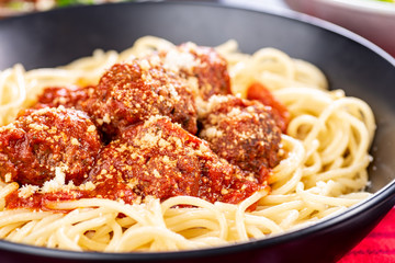 Traditional Italian spaghetti and meatballs in a round bowl on a red tablecloth