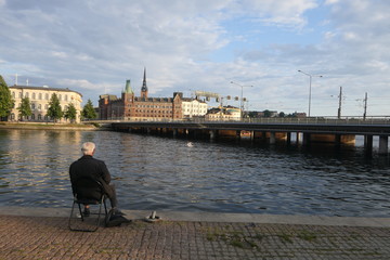 alter Mann sitzt an Wasser