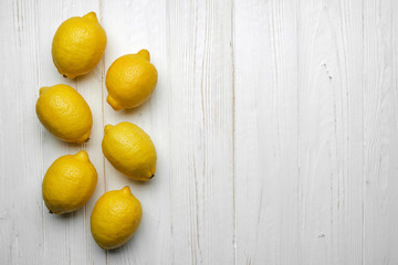 fresh whole yellow lemons on white wood background with space for text. top view