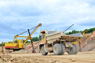 Big mining truck amid huge excavators in an open-pit  dolomite quarry. Loading and transportation of stone ore in a limestone quarry. Excavator and heavy mining dump truck © MaxSafaniuk