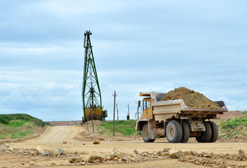 Big yellow dump truck working in the limestone open-pit. Loading and transportation of minerals in the dolomite mining quarry. Belarus, Vitebsk, in the largest i dolomite deposit, quarry 