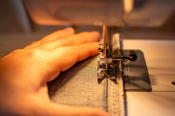 Hand sawing the jeans fabric on the sewing machine