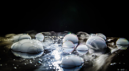 Rainbow soap bubbles on a dark background. Abstract wet surface with fog and light