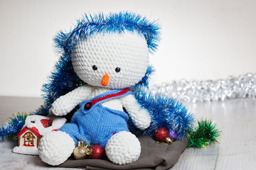 Сrocheted soft toy snowman in blue pants on table,close-up,space for text.Celebrating christmas - winter concept