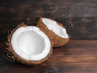 Two halves of fresh coconut on a dark wooden background. Copy space.