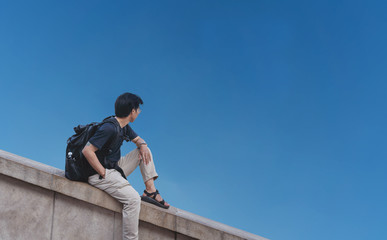 a man with backpack looking at clear blue sky in summer