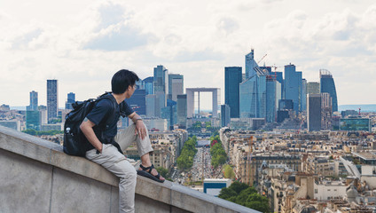 a man with backpack looking at Paris cityscape in France