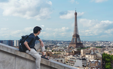 a man with backpack looking at Eiffel tower, famous landmark and travel destination in Paris, France
