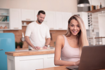 young female freelancer working on laptop in kitchen