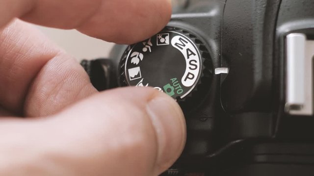 Setting mode dial lock button of the camera reflex - macro. Fingers switched camera settings.