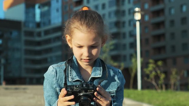 Little girl photographer looks at pictures on his camera