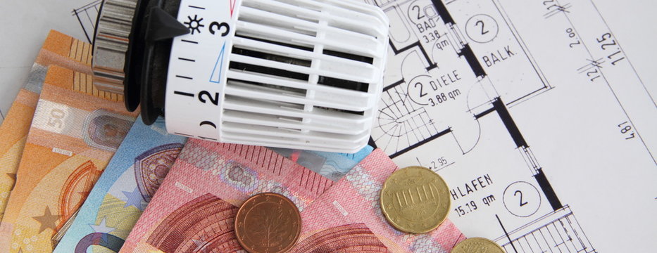 Heizungsthermostat mit Geldscheinen auf einem Bauplan