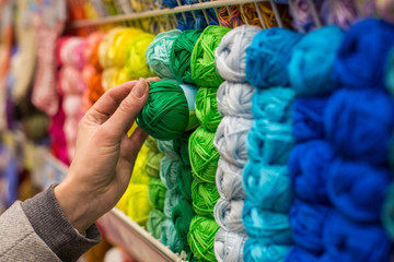 Close Up of yarn balls. Girl hand choosing Yarn in Knitting Shop. knitting shop center. A lot of...