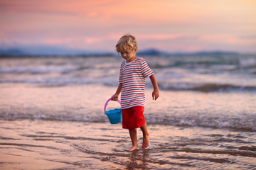 Child playing on ocean beach. Kid at sunset sea.