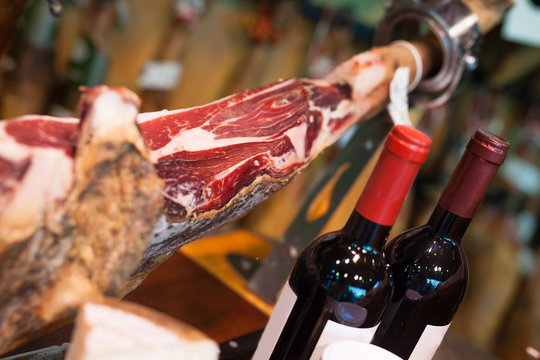 Still life of spanish pork jammon on holder, bottles of wine cheese and olives