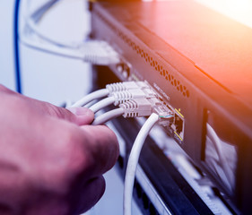Technician connecting network cables to switches. Connecting cables in server cabinet.