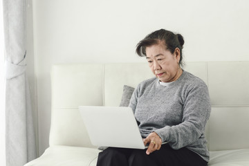 Asian senior woman using laptop at home, lifestyle concept.