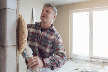 Plasterer smoothing interior wall of new homes with machine