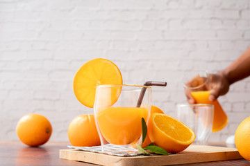 Wood table with Glasses of Freshly Squeezed Orange juice with Human hand pouring orange juice, No...