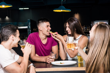 Cheerful friends in the pub. Drinking beer, eating pizza, talking, having fun.