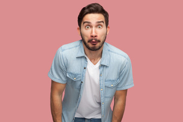 Portrait of surprised handsome bearded young man in blue casual style shirt standing and looking at...