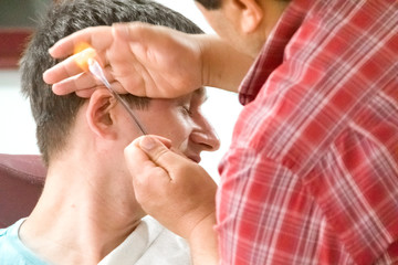 Young man at the hairdresser. Hair removal in the ears.