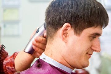 Fototapeta premium Barbershop. The process of cutting the hair of a young man.