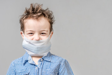 Laughing boy in the medical mask on a gray background. Isolated.