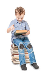Cute smiling boy with a book is sitting on a pile of books. Isolated.