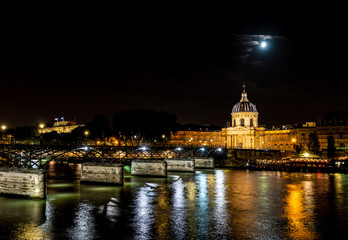 Fototapeta na wymiar Institut de France and people walking on Pont des Arts at night - Paris, France.