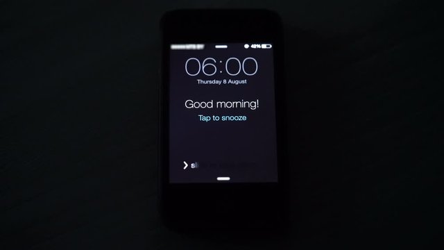 Good morning alarm clock on the phone in the dark room, close-up
