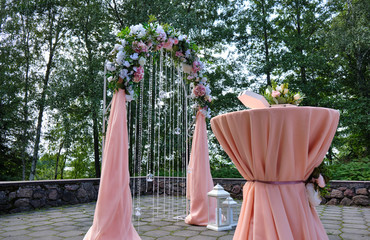 Photo of a beautiful wedding decoration with arch flowers for the newlyweds. Made in the summer park.