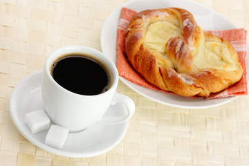 cup of coffee and Cheese Danish on table