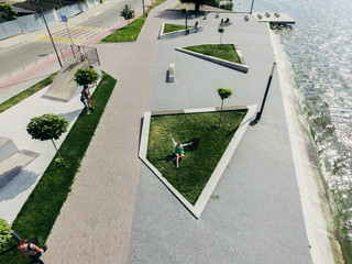 Funny girl is sitting on a green lawn near a lake in a recreation area of the city embankment....