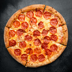 Tasty Pepperono Pizza Sliced On Black Concrete Background. Table Top View. Fast Food