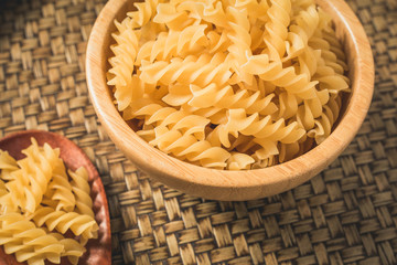 Raw macaroni in a bowl and ladle wood. Italian food style.