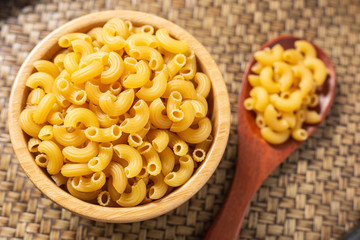 Raw macaroni in a bowl and ladle wood. Italian food style.