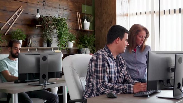 Young businessman talking with his data analist to find the right solution. Intern working in the background.