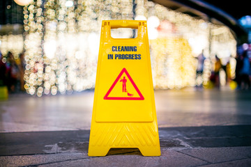 Sign showing warning of wet floor out door at night with bokeh light background