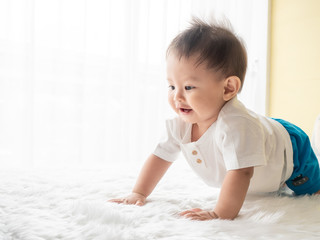 Portrait happy baby boy is crawling on white carpet in the room. Asian baby boy is crawling and...