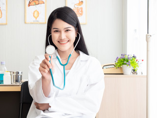 Portrait of a woman doctor and holding stethoscope in the examination room. Happy beautiful doctor and smiling in hospital or clinic.