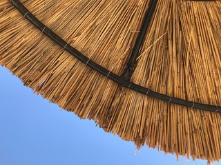 Bamboo sun umbrella against blue sky 