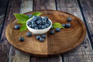 Black currant fresh ripe currant berries on a old vintage wooden table with green leaves. Juicy natural fruits currant.