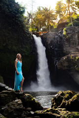 Travel lifestyle. Young traveler woman at waterfall in tropical forest, Ubud, Bali. Tegenungan waterfall.