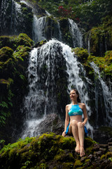 Travel lifestyle. Young traveler woman sitting at waterfall in tropical forest. Banyu Wana Amertha waterfall Wanagiri, Bali, Indonesia.