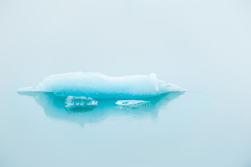 Blue iceberg in Jokulsarlon glacial lagoon in foggy day, southern Iceland.
