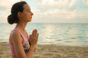 Namaste mudra. Young woman meditating, practicing yoga and pranayama with gyan mudra at the beach,...