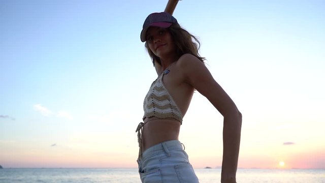 Young beauty girl dansing at tropical beach near sea water at paradise island at sunset, close up. Summer concept. Holiday travel.