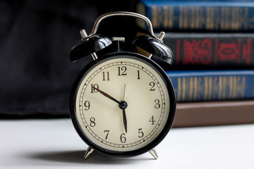 Black retro alarm clock with books on a dark background. Morning concept. Picture for wallpaper with place for text